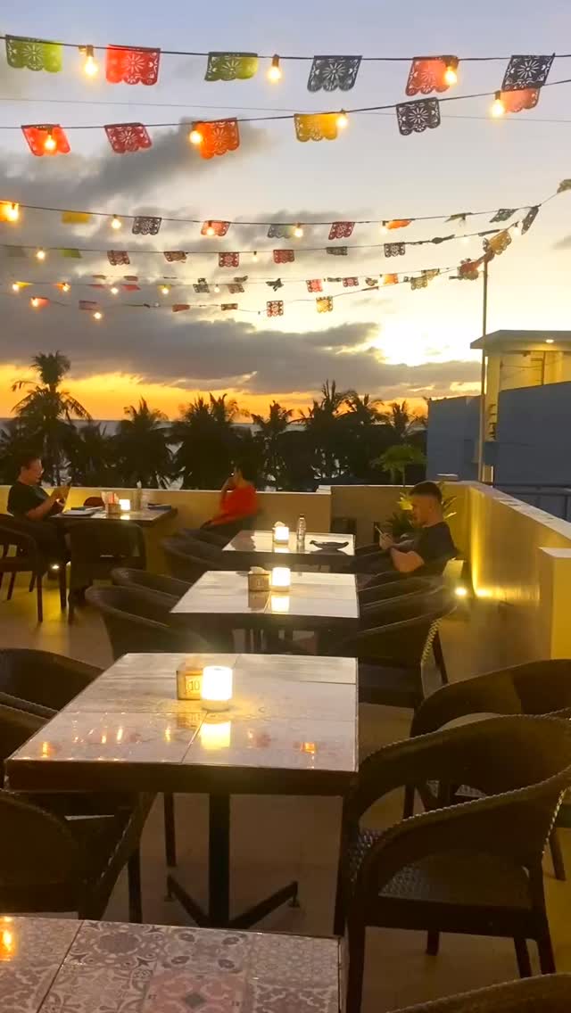 Rooftop restaurant at sunset with colorful papel picado flags and string lights